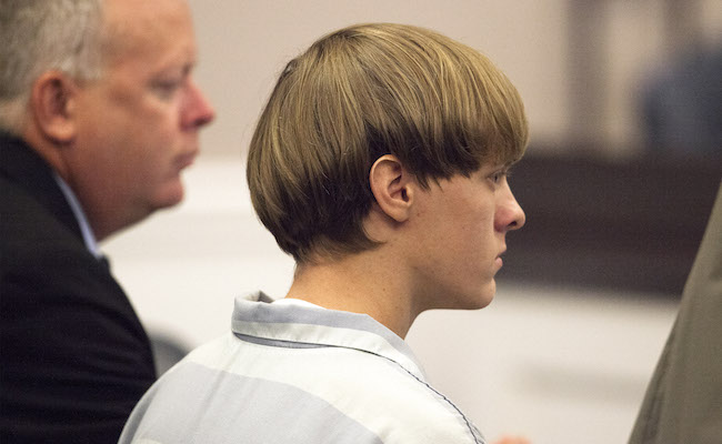 Dylann Roof (R), the 21-year-old man charged with murdering nine worshippers at a historic black church in Charleston last month, is helped to his chair by chief public defender Ashley Pennington during a hearing at the Judicial Center in Charleston
